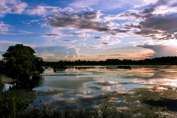 Ukraine. Sunset over the lake. The sun
shines through the clouds on the horizon.
The sky with clouds is reflected in the lake.
