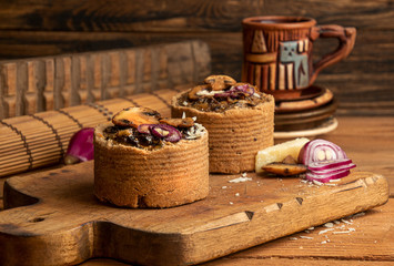 Tarts with mushrooms, caramelized red onion and cheese over on old wooden rustic background.