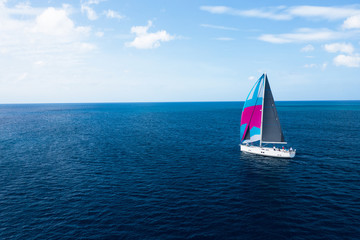 Fototapeta premium Small pleasure yacht in a paradise bay of a tropical ocean, top aerial view