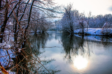 Winter landscape. The lake among the winter park. Trees are in the snow and are reflected in the water ..