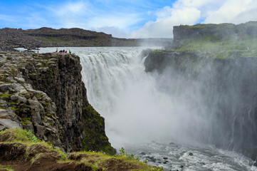 Dettifoss Falls in Northern Iceland In the daytime of the summer there are tourists taking pictures and watching greatness.