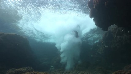 A man jumping into the sea wearing a suit jacket