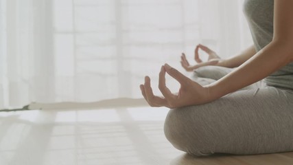 Hand of women in lotus pose while sitting at the floor and curtain white in the morning sunlight at home. Dolly shot, Concept of relaxation and meditation