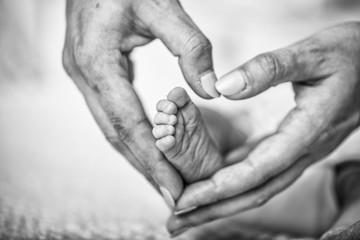 Newborn baby feet in mother hands. Masseur massaging little baby's foot, shallow focus. Newborn baby feet in mother's hands. Mother making massage of child's foot.