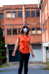 A young woman with a mask outside her factory wearing a mask. Health emergency, pandemic Covid-19