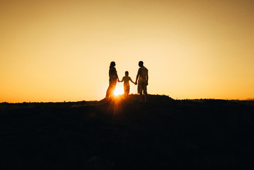 silhouettes of a happy young happy family against an orange sunset