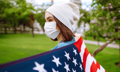 Young girl in a protective mask with the flag of America. Independence Day of America. 4th of July....