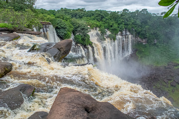 View of the Kalandula waterfalls on Lucala river, tropical forest and cloudy sky as background