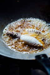 Frying squid in boiling oil in wok