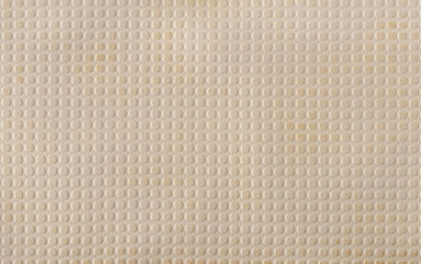 Beige faux leather with a pattern of evenly repeating small circles. A variety of textures of artificial materials. Background.