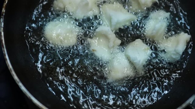 Onion vada with hot oil boiling in cooking pan closeup view, Indian dish making in a traditional home method , some area this is called ulli vada.