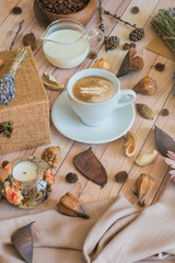 Still life details of home interior. A cup of coffee with milk on a wooden table. The concept of coziness and home atmosphere. Cozy autumn composition