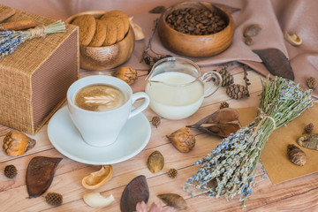 A cup of coffee, milk, coffee beans, oatmeal cookies on a wooden background. Cozy autumn composition. Morning breakfast. Autumn mood