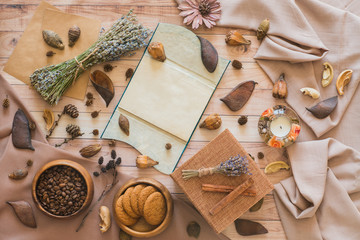 Fototapeta na wymiar A notebook, coffee beans, oatmeal cookies, gift box, and lavender on a wooden background, flat lay. Autumn background top view, space for text. Layout with free text space