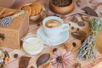 Autumn layout, flat lay. Details of still life with decoration. A cup of coffee, milk, coffee beans, oatmeal cookies on a wooden background.