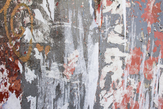 Old dirty urban wall with torn paper posters and peeling paint texture background.