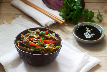Oriental style vegetable salad with eggplant, soy sauce and chopsticks on a wooden table. Rustic style.