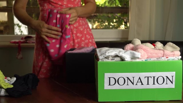 A woman disposes of used or old baby textiles, clothes, shoes, accessories, linen by donating them to charities