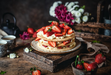 cake with fresh strawberries and cream cheese on wooden board, rustic wooden background, seasonal dessert
