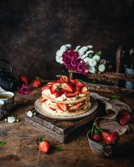 cake with fresh strawberries and cream cheese on wooden board, rustic wooden background, seasonal dessert
