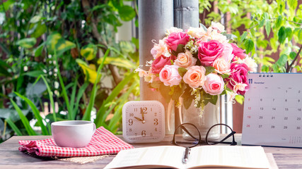 Calendar for Planner to plan daily timetable, appointment, organization and meeting agenda on desk, work from home. Desktop Calender, Cup of Coffee, vase of rose and clock place on wooden table.