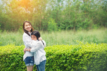 Fototapeta premium Asian mother and Kid playing together in nature park. Mother and Daughter greeting and hug, I Love you mom. Happy family in mother's day concept.