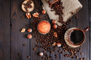 hot fragrant coffee in a vintage clay cup and coffee beans with nuts on a dark wooden background
