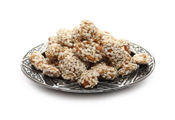 Honey covered, coated peanuts with sesame seeds, savory snacks on metal plate, bowl isolated on white background