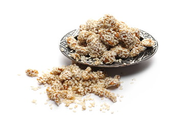 Honey covered, coated peanuts with sesame seeds, savory snacks on metal plate, bowl isolated on white background
