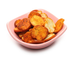 Bruschette chips, grilled bread crisps with tomatoes, olives and oregano, savory snacks in porcelain bowl isolated on white background