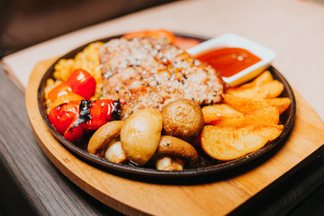 A piece of tasty grilled chicken steak covered with sauce on a plate served with grilled  tomatoes