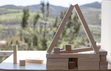 Building from wooden cubes and rods. A photo was taken on the table. Forest mountain landscape in the background. Close up.