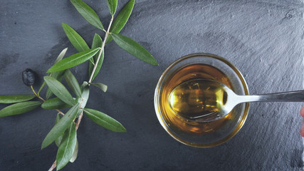 Extra Virgin oil. A tablespoon hold on the olive oil. Healthy food, genuine Italian ingredient, natural product, dark background.