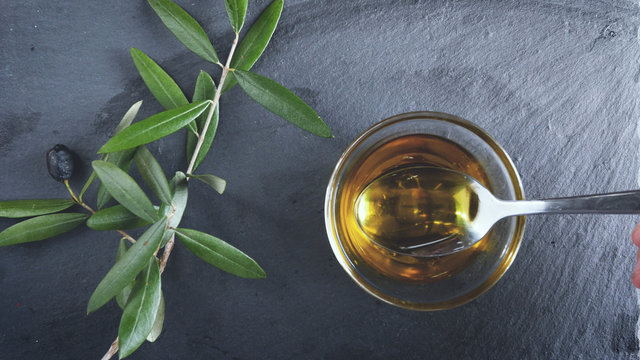 Extra Virgin oil. A tablespoon hold on the olive oil. Healthy food, genuine Italian ingredient, natural product, dark background.