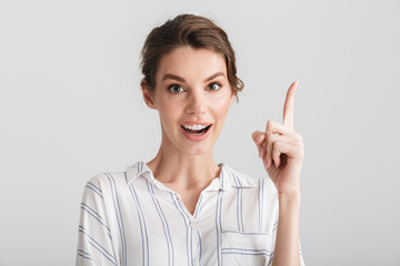 Image of excited caucasian woman smiling and pointing finger upward