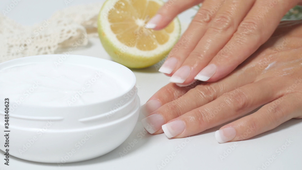 Wall mural  natural skin care, applying natural white cream on hands. Moisturizing treatment skin with natural ingredients. Cream, lemon, officinal herbs.