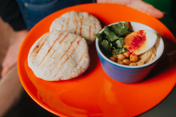 Traditional eastern hummus and pita bread served with chickpeas, boiled egg and parsley.