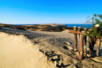 View of diagonal nordic dune rib and protective fences of wood, pine branches, hills and Baltic sea...