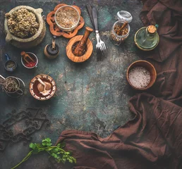 Tuinposter Rustic food background with vintage kitchen utensils. Herbs and spices in wooden bowls, olives oil and napkin. Frame. Top view. Copy space for your product or design © VICUSCHKA