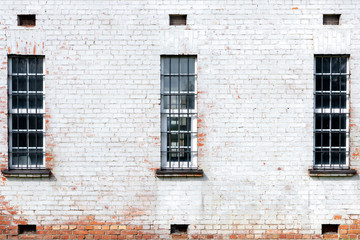 Front view of three old windows with iron grating,white brick home wall texture.