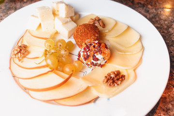 Cheese platter with different kinds of cheese served with walnuts, almond nuts and honey. Parmesan cheese, Dorblu cheese