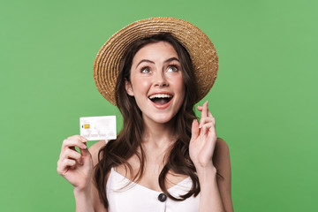 Image of excited woman holding credit card and fingers crossed