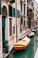 Fototapeta na wymiar Moored boats at the walls of houses in the water in Venice. Narrow deserted canal between houses, azure sea water at the foot of the house.