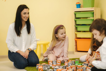 Naklejka premium Childres sits with techers on the floor and learning. Preschool