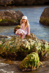 Happy pretty girl walks along the sea coast against the background of the sea, from behind a beautiful landscape