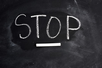 inscription english stop with white chalk on a black blackboard