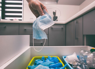 The woman throwing the used medical mask to the trash bin with gloves and masks