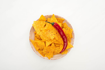top view of corn nachos with red chili pepper on white background