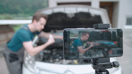 Smartphone recording a car specialist influencer checking oil