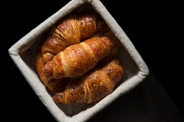 French croissants in a basket isolated on black background